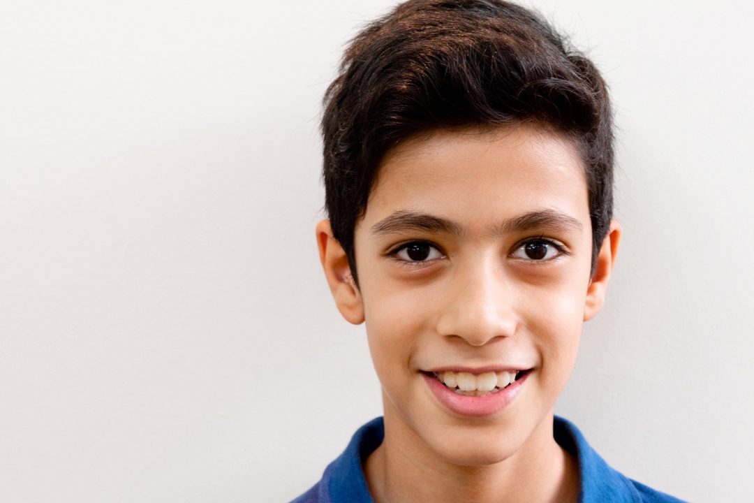 Outdoor portrait of a smiling young boy in a blue shirt