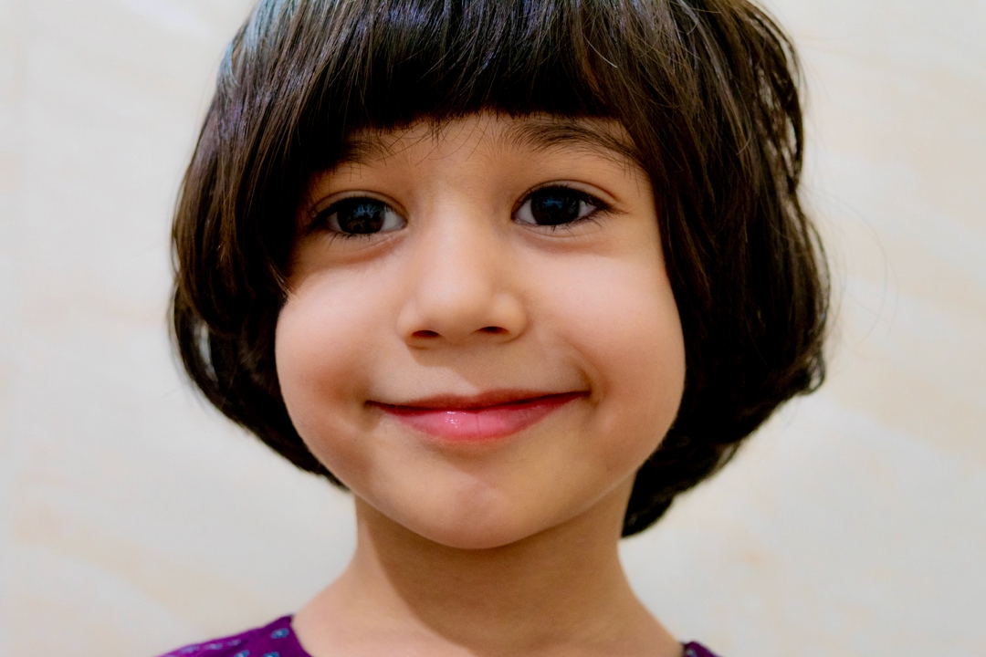 Close-up portrait of a young child with dark hair and a purple top