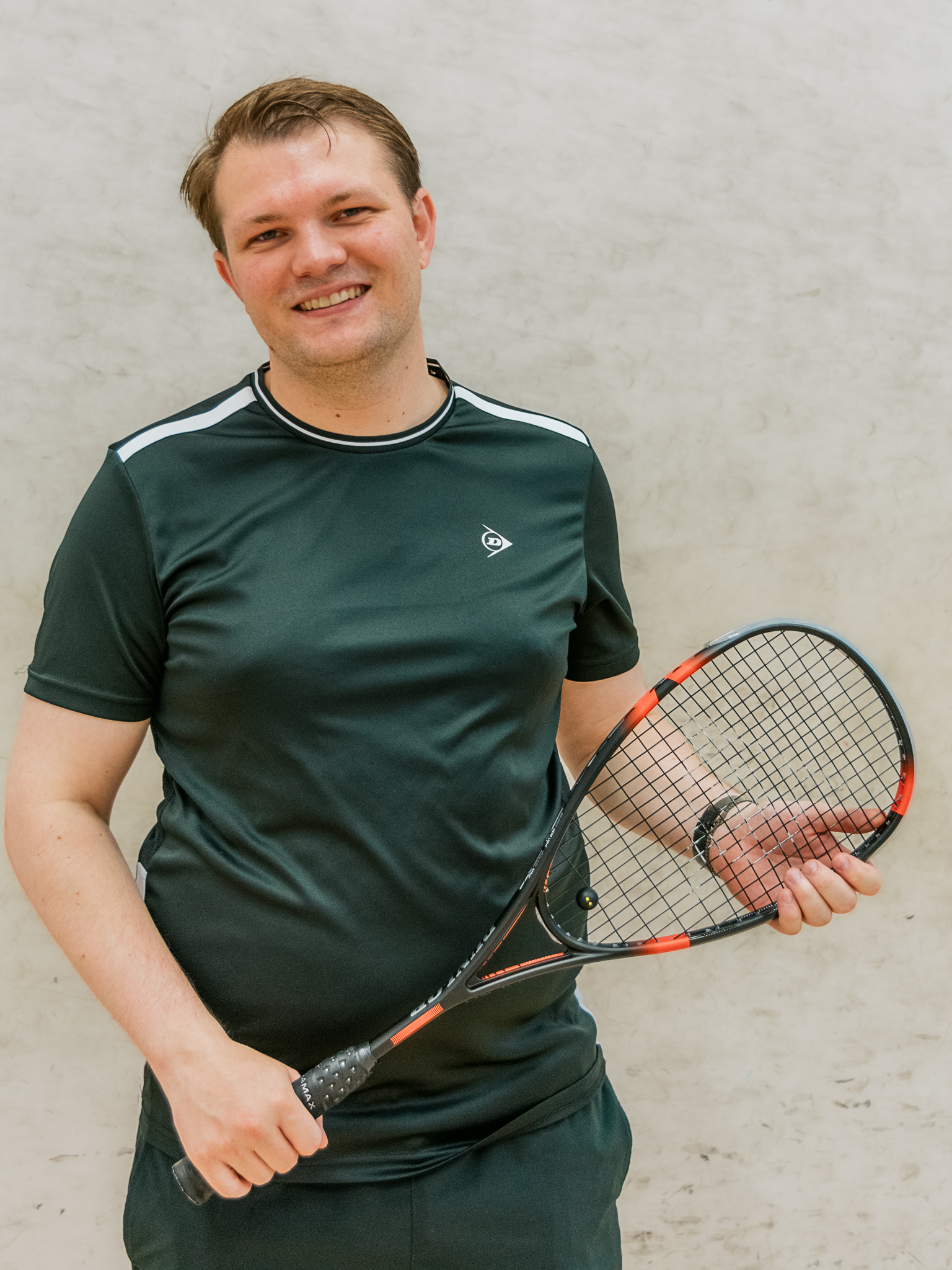 Portrait of a smiling squash player holding a racket