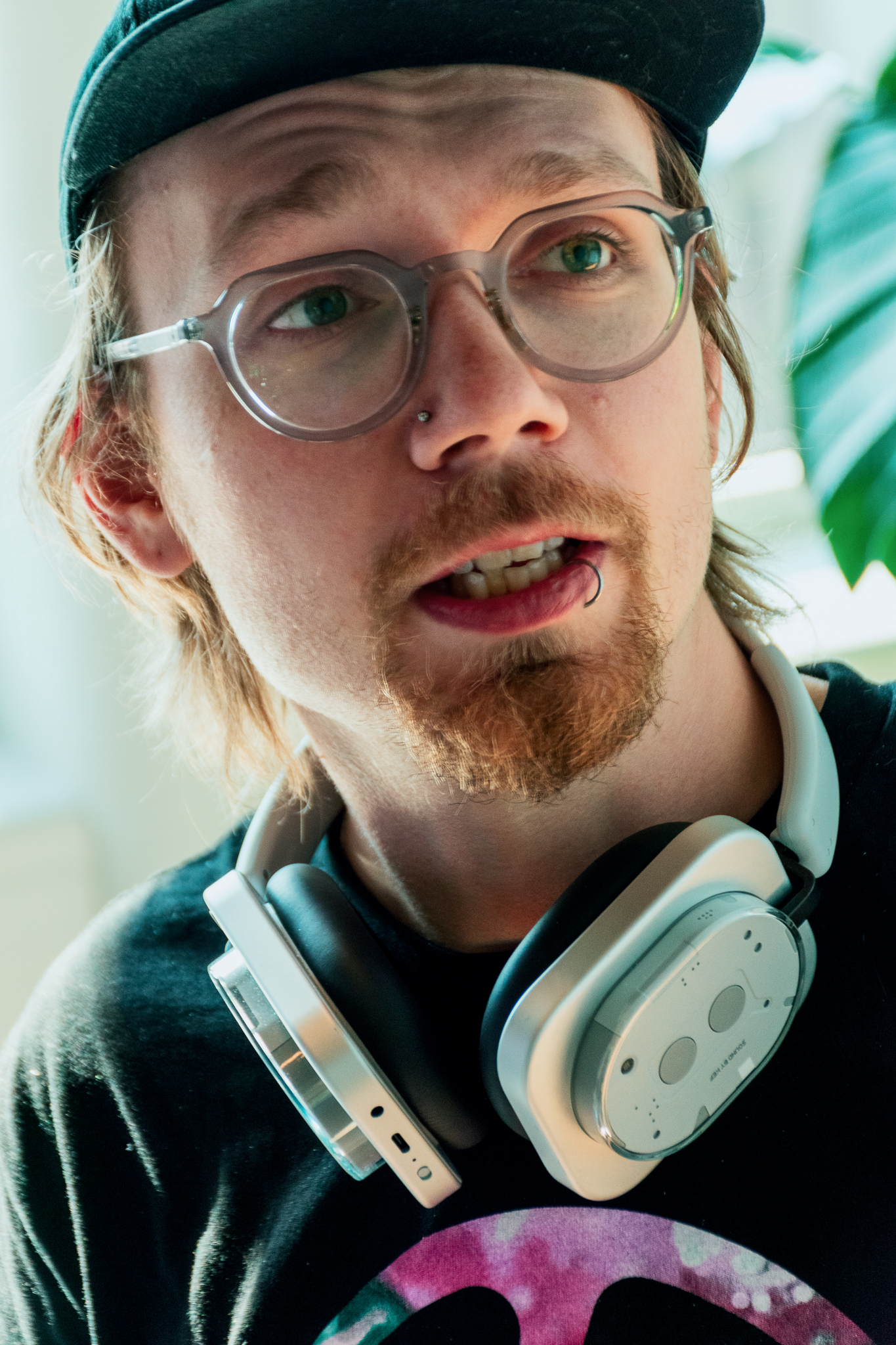 Close-up portrait of a man wearing glasses, a cap, and headphones