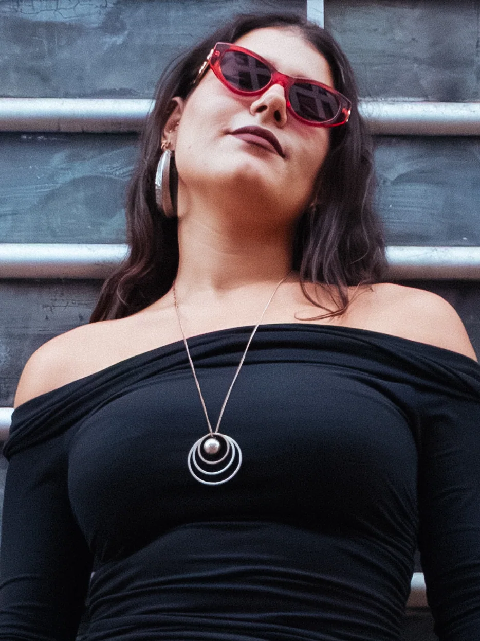Fashion portrait of a woman wearing red sunglasses and a black off-shoulder top